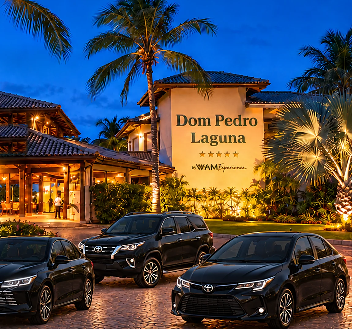 Entrada de resort iluminada à noite, com dois sedãs e um SUV executivos