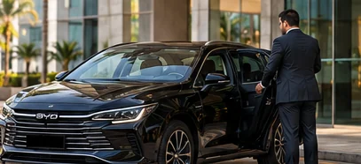 Motorista de terno abre a porta de um sedã BYD preto